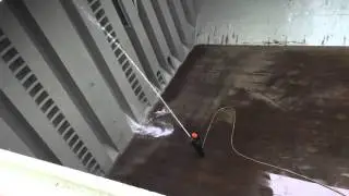 Ship crew cleaning lower areas of cargo holds using high pressure washer