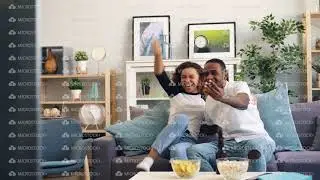 African American couple enjoying sports on TV hugging and laughing having fun