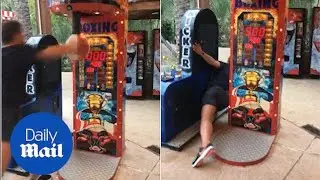 How STRONG!: Hilarious moment man punches bag game but falls - Daily Mail