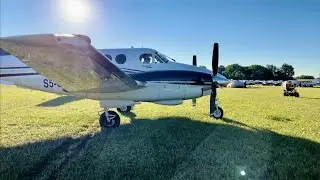 A Beech C90 King Air at Oshkosh AirVenture in the grass.