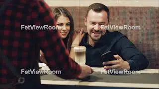 A man with a beard and an attractive brunette are sitting in a bar and watching the phone.