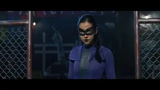 A masked female vigilante battles some guys in a cage fight