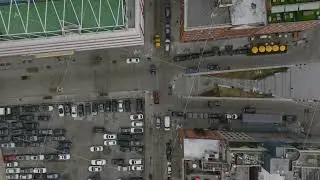 Top down panning footage of streets and multistorey buildings in city district. Vehicles standing on