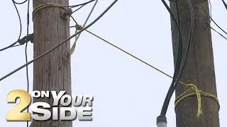 Despite efforts, leaning utility pole secured by rope until company moves cable