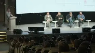 Panel discussion at conference stage with speakers and audience