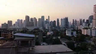 Aerial view flying over residential buildings towards modern downtown Bangkok skyline with its tall