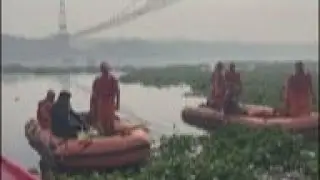 Officials probe India bridge collapse as divers search river