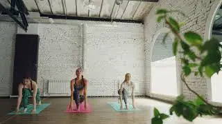 Young slender women are having morning yoga class doing sun salutation complex on bright mats in
