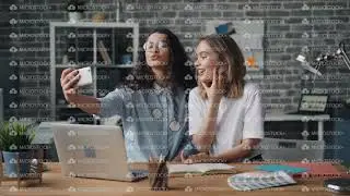 Beautiful young women partners taking selfie in office using smartphone camera