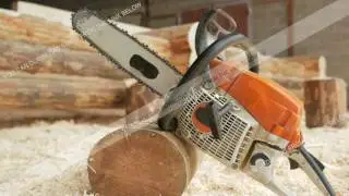 Chainsaw builder at the site of construction of a wooden house. Many sawdust and a part of the