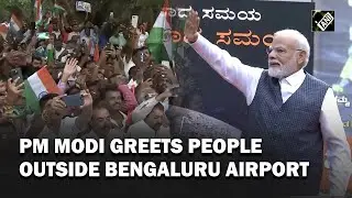 PM Narendra Modi greets people gathered outside HAL Airport in Bengaluru