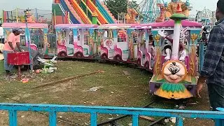 Kids playing in festival fair with train and helicopter.