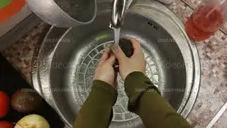Closeup personal perspective of female hands washing ripe avocado in sink