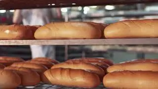a male baker in a white uniform takes out of the oven just baked bread
