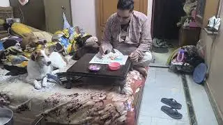 One dog is chilling while other dog is eating dinner  with human dad who did not want dogs in house 