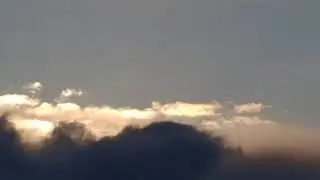Grey Clouds Pass By In Front Of Bright White Clouds In The Winter Evening Sky