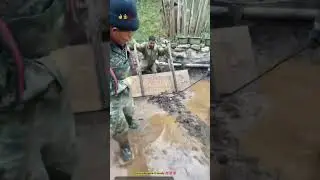 Сельский житель использует деревянную доску, чтобы очистить улицу от грязи.