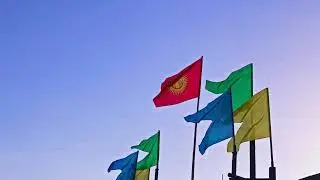 National flag of Kyrgyzstan with yellow, green and blue flags on evening blue sky background
