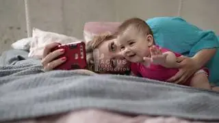 Mother and baby taking selfie with phone in bed