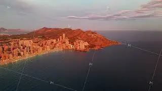 Early morning glow enhances lively seaside cityscape against serene mountains and peaceful sea