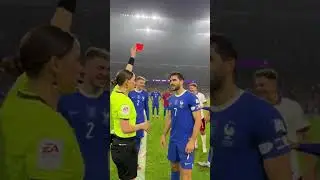 female referee halts the match and firmly raises a red card toward a male player
