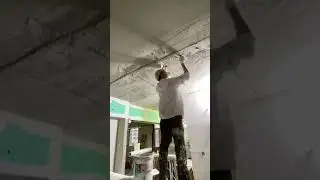 Professional worker applying plaster to the ceiling smoothly