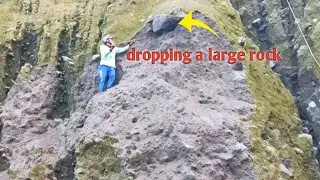 miners work together to drop a large rock from a cliff