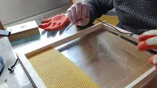 Fixing wax foundation strip onto a Layens frame.