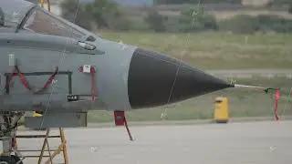 Military jet with external fuel tank on ground