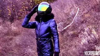 WALKS IN THE SCAFANDER IN ANCIENT RUINS. BLUE SHINY WINTER JUMPSUIT WITH HOOD AND BLACK HELMET