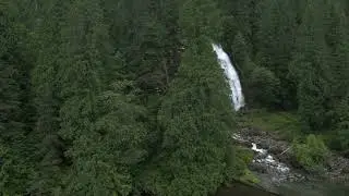 Aerial of Chatterbox Falls revealed behind trees by Princess Louisa Marine Provincial Park, Egmont