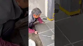 laying the dark grey square tiles on the ground with white grout for a neat and durable floor finish