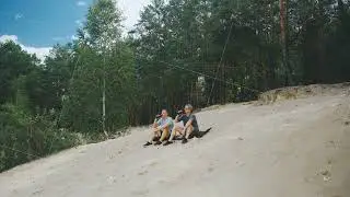 Two white men sitting on sand dune near forest, business partners taking contemplative break, casual
