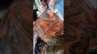 The pigments blend with the water waves, and the colorful patterns flow gracefully in the ripples.