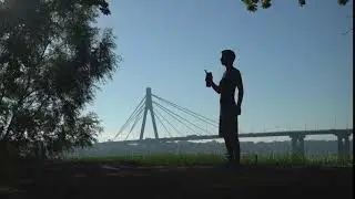 silhouette of athletic young male standing hectares of lawn with sand and drinking from a bottle out