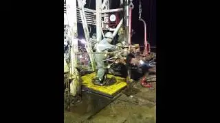 Iron roughneck - hand throwing tongs on a double kelly rig in west texas