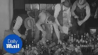 Prohibition era agents empty liquor bottles into drains - Daily Mail