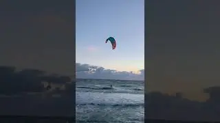 Kitesurfer catches the currents of the sea wind, cutting through the high waves of sea