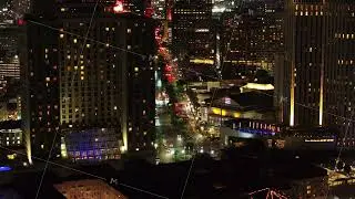 Aerial view of lively downtown New Orleans at night, featuring bright buildings, bustling streets