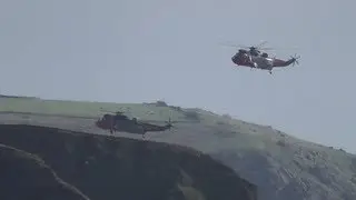 Gunwalloe Cove two RNAS Culdrose 771 helicopters training over Church Cove area (Two red noses)