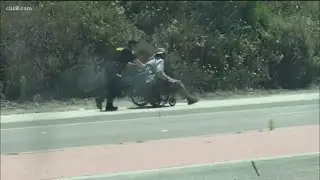 Oceanside police officer helps man in wheelchair up steep hill on El Camino Real