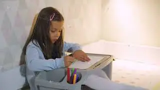Child drawing at bedside, Girl creating art during resting time, Young girl focused on colorful