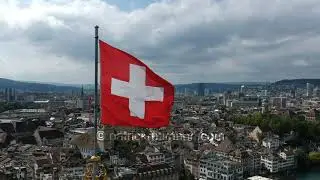 Drone shot of Swiss flag waving in the wind over Grossm&uuml;nster in Z&uuml;rich, Switzerland