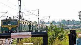 Two EMU Local trains run through a smooth curve and in front of a level crossing
