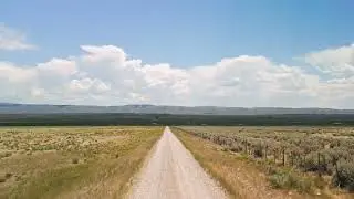 Stock Video - Aerial view flying over a dirt road leading off into the landscape in Wyoming