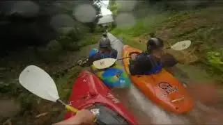 Three friends are kayaking down a drainage ditch side by side!