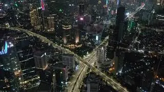 Wide aerial dolly shot of highway intersection in large modern city with skyscrapers at night