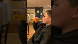 Ребенок притворяется, что пьет пиво в пабе (это яблочный сок)