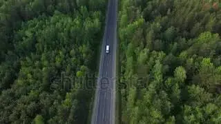 stock footage aerial view flying over old patched two lane forest road with cars van moving green tr