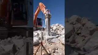 Excavator breaking big stone with rock breaker attachment
